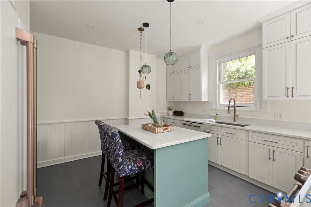 109 N Morris Street, The Fan, Richmond, VA 23220 Crisp white cabinetry, a center island with countertop seating, stainless steel appliances, a single-basin sink with a gooseneck faucet, and durable tile flooring