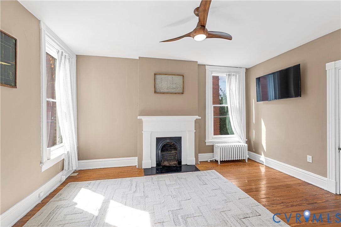 109 N Morris Street, The Fan, Richmond, VA 23220 Hardwood flooring, fireplace with white mantel, two windows, ceiling fan, and neutral wall tones