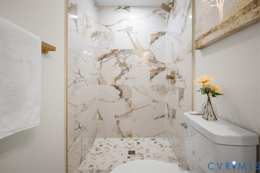 3510 Hanover Avenue, Museum District, Richmond, VA 23221 Shower with large format marble-look tile, gold-finish fixtures, and a pebble-tiled shower pan