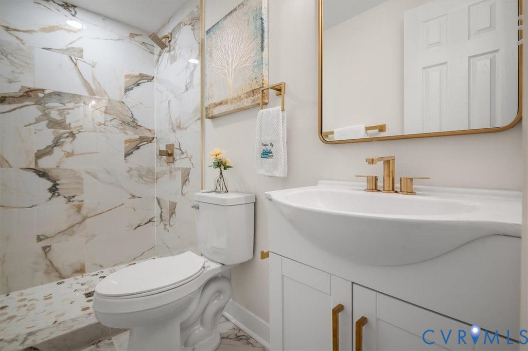3510 Hanover Avenue, Museum District, Richmond, VA 23221 Walk-in shower with large format tile and mosaic flooring, white toilet, vanity with integrated sink, and gold-finish fixtures
