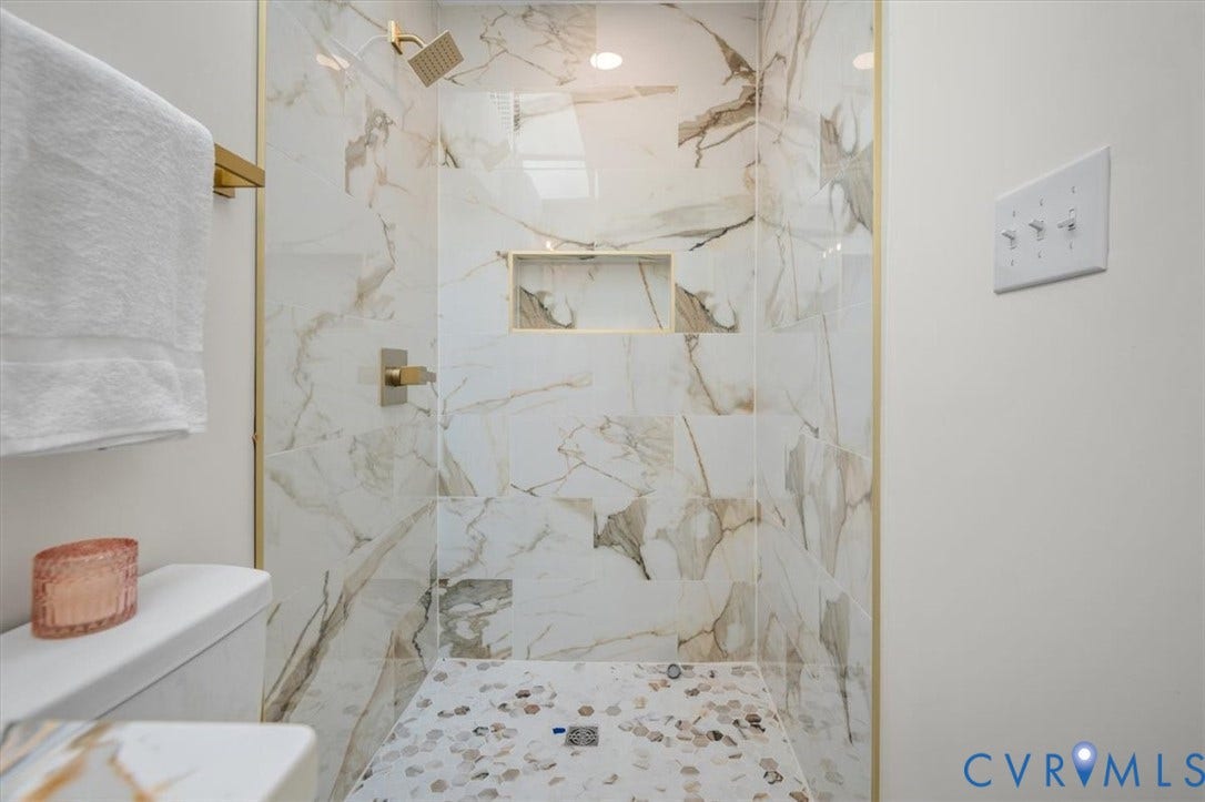 3510 Hanover Avenue, Museum District, Richmond, VA 23221 Shower with large format veined wall tile, mosaic pebble-style floor tile, built-in shower niche, and gold-toned fixtures