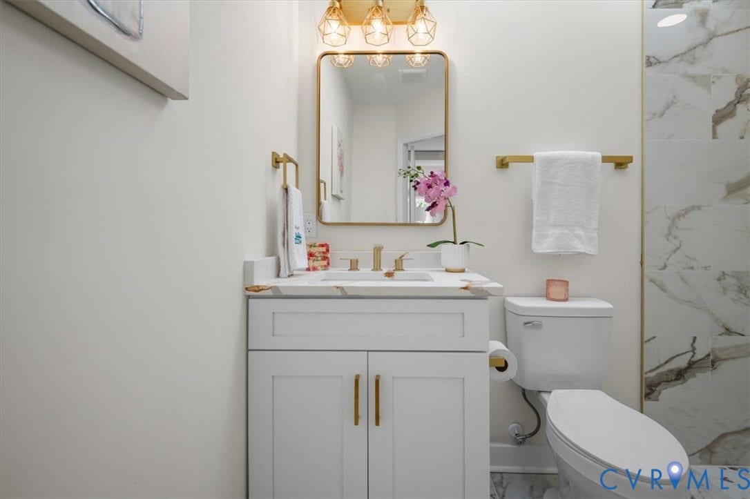 3510 Hanover Avenue, Museum District, Richmond, VA 23221 White vanity with gold hardware, wall-mounted rectangular mirror, brass finish lighting fixture, and a toilet