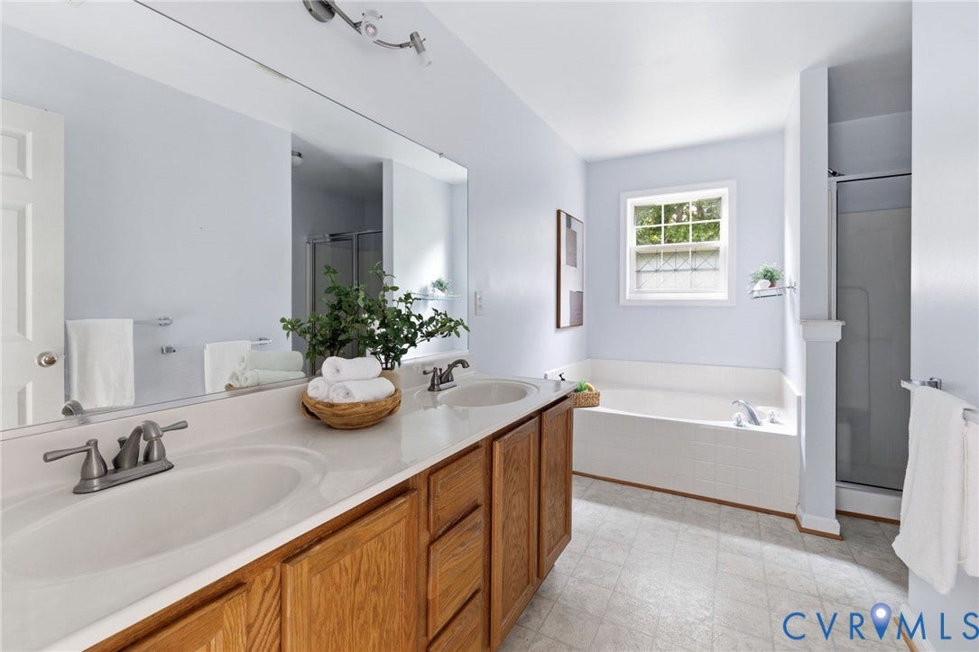 3173 Poplar View Place, Ashley Forest, Chester, VA 23831 Dual basin vanity with wood-finish cabinetry and an integrated bathtub