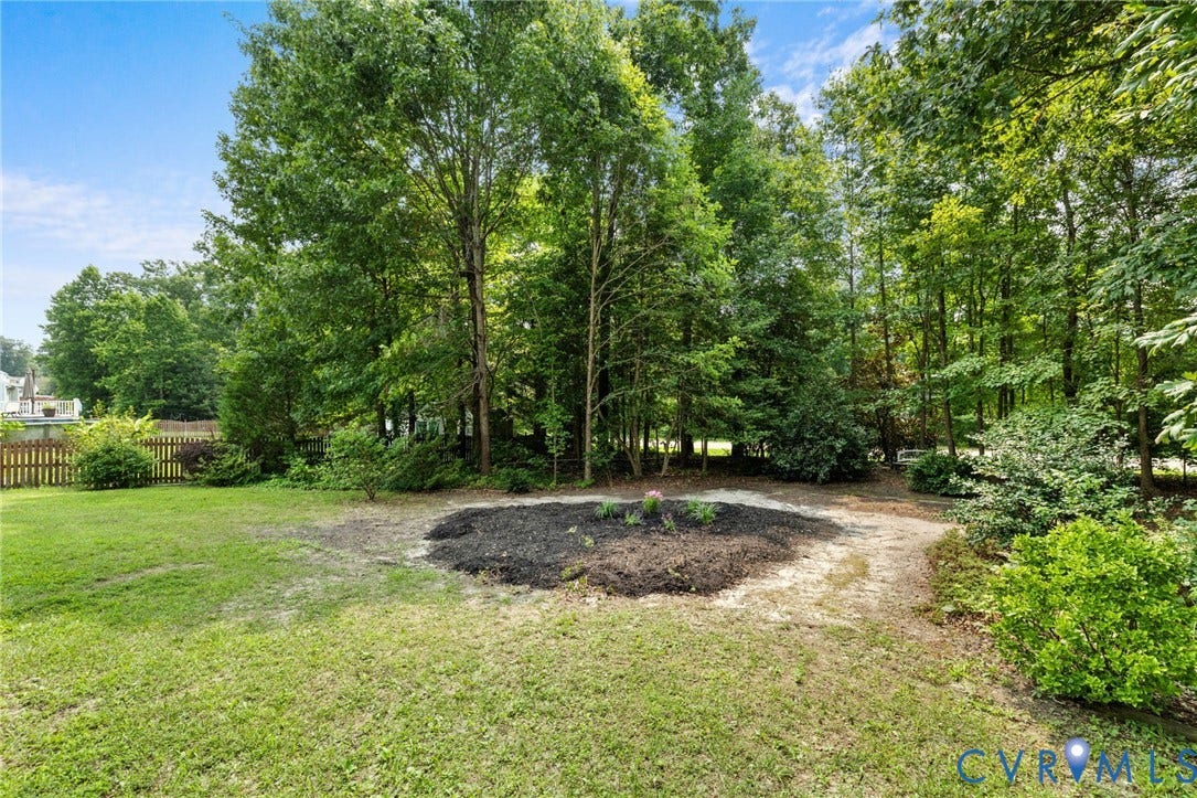 3173 Poplar View Place, Ashley Forest, Chester, VA 23831 Expansive lawn with a treed perimeter, featuring a garden bed and a wooden fence
