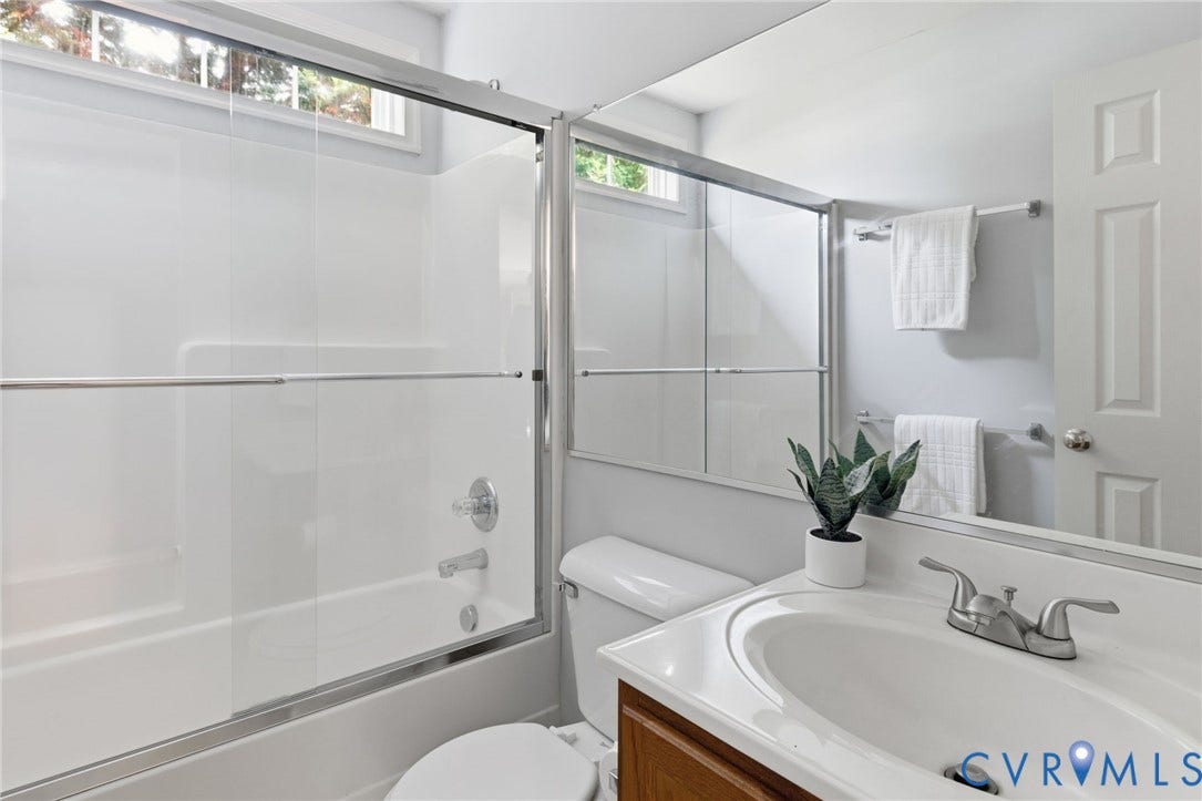 3173 Poplar View Place, Ashley Forest, Chester, VA 23831 Built-in white bathtub with sliding glass enclosure, chrome fixtures, and an integrated window