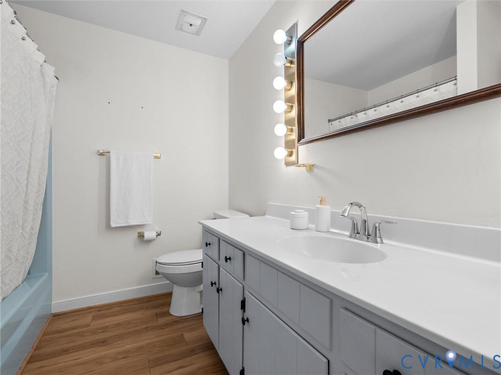 White vanity with integrated sink, chrome faucet, and wood-finish flooring