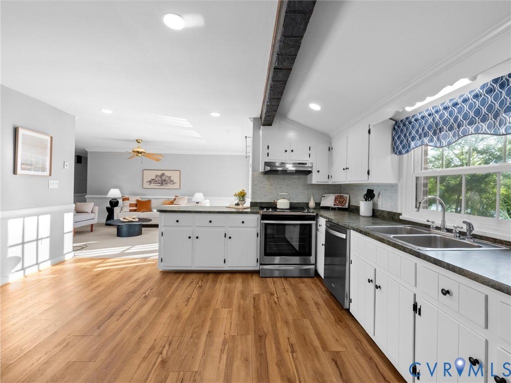 Kitchen featuring wood-finish flooring, white cabinetry, stainless steel appliances, and a double basin sink