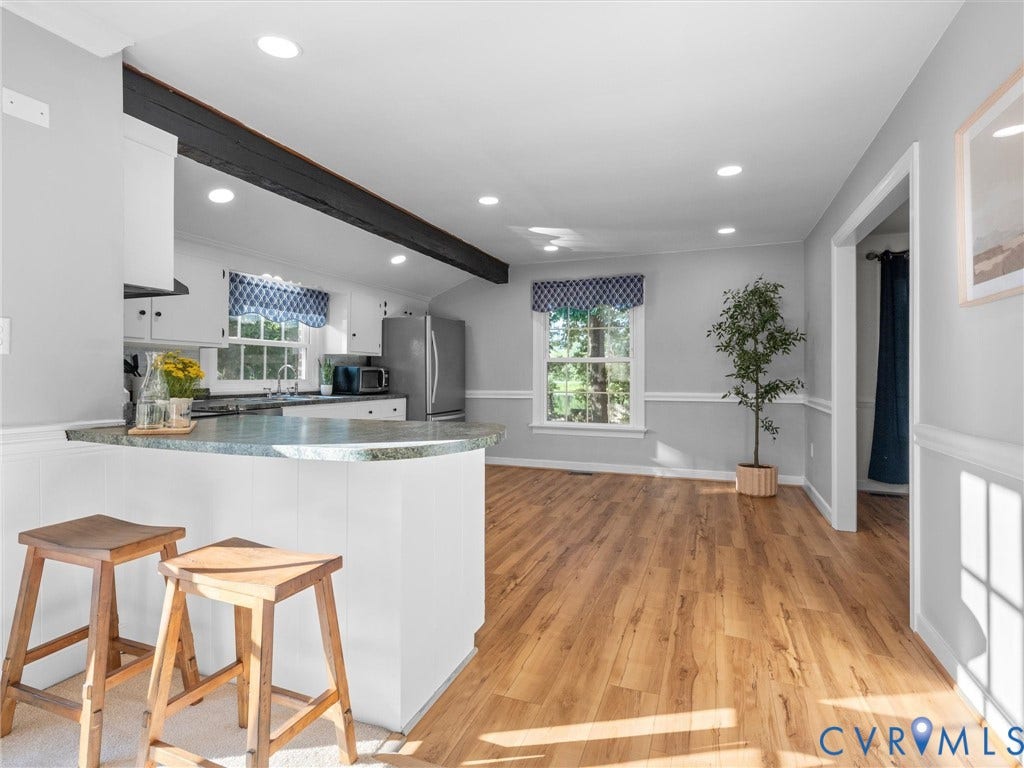 Kitchen with a breakfast bar, recessed lighting, wood-finish flooring, and a window with a valance