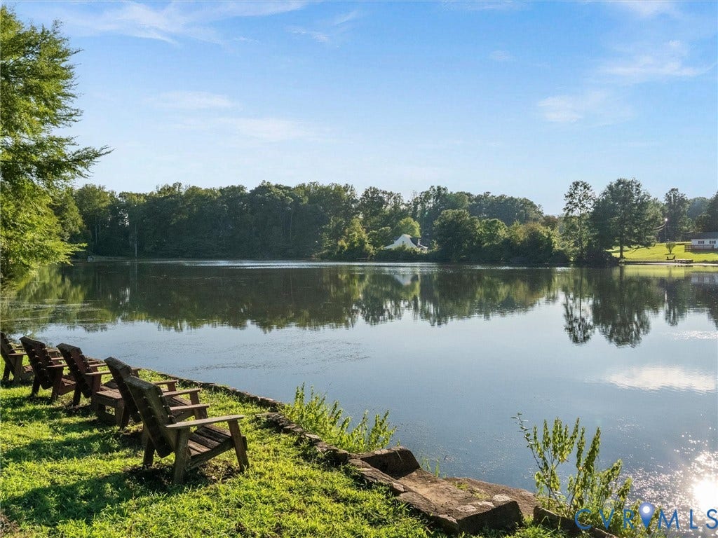 Lakefront property featuring a grassy bank and distant tree line