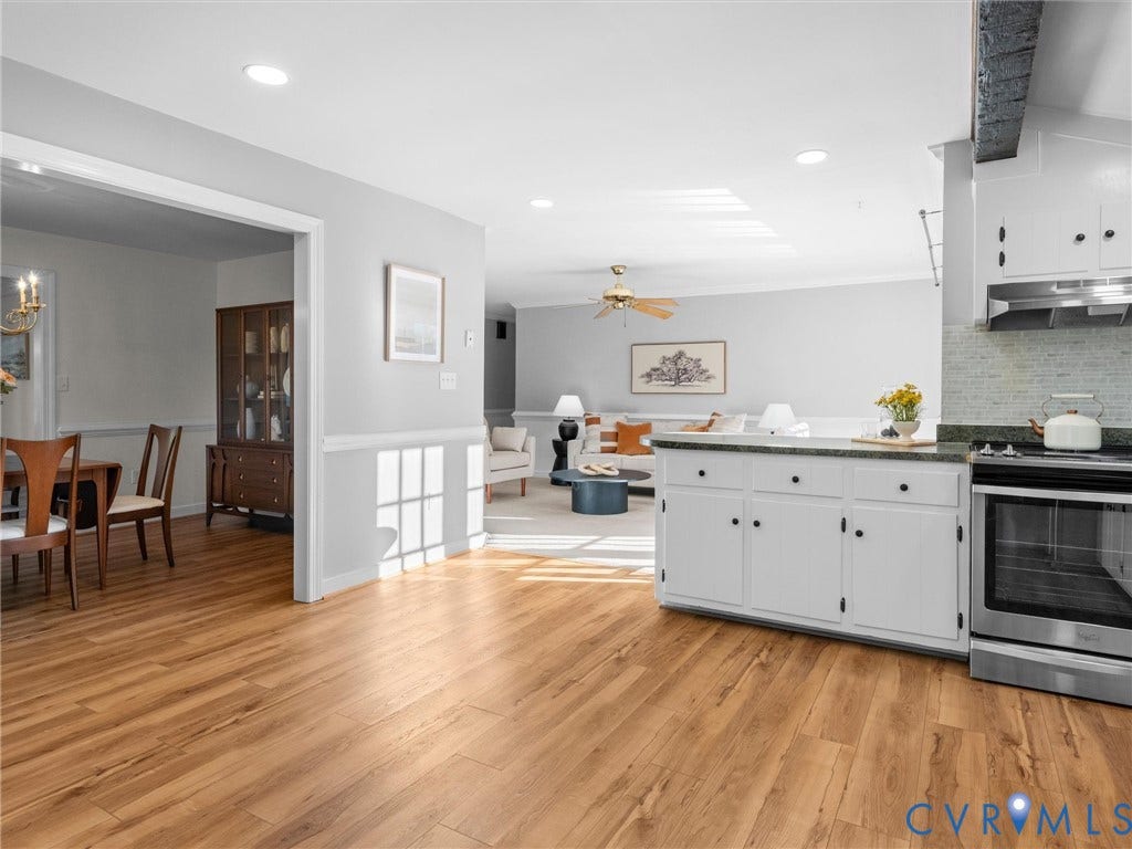 Open-concept living space with wood-finish flooring, white cabinetry, a tile backsplash, and recessed lighting