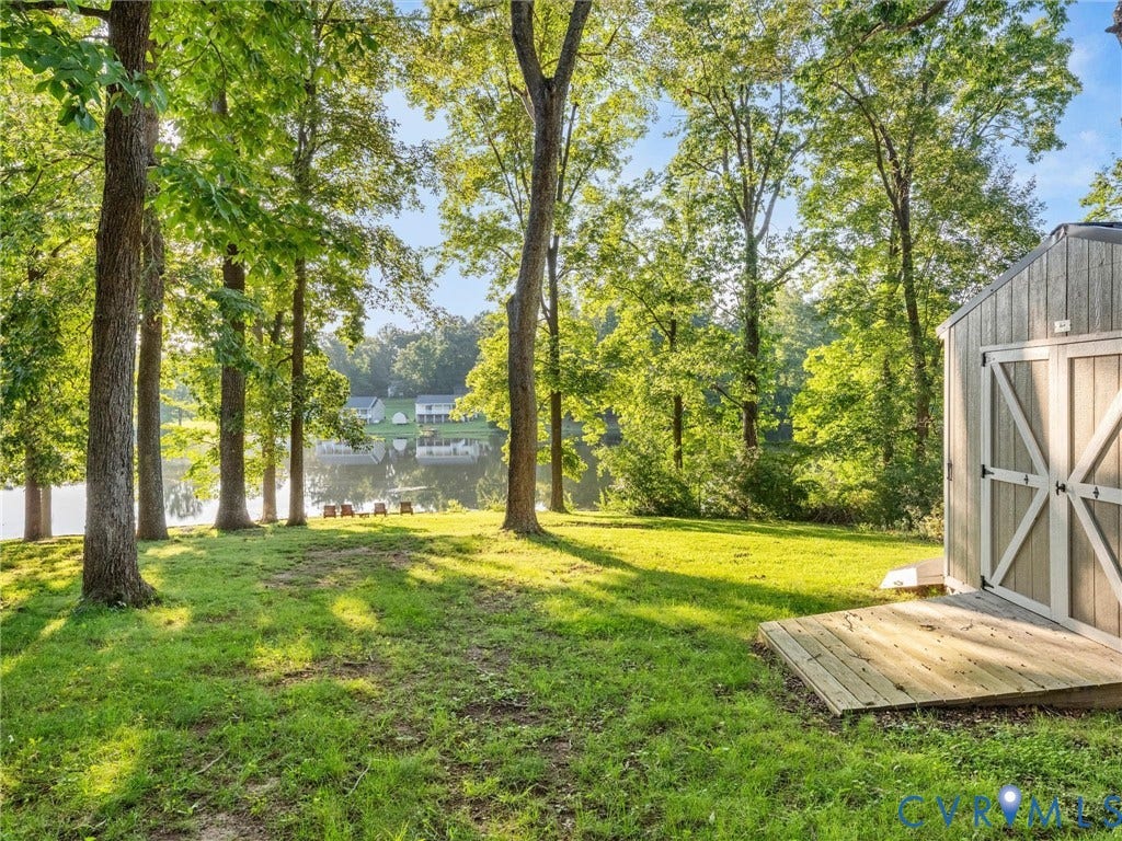Expansive greenspace with mature trees, a detached storage shed, a wooden shed deck, and a waterfront setting