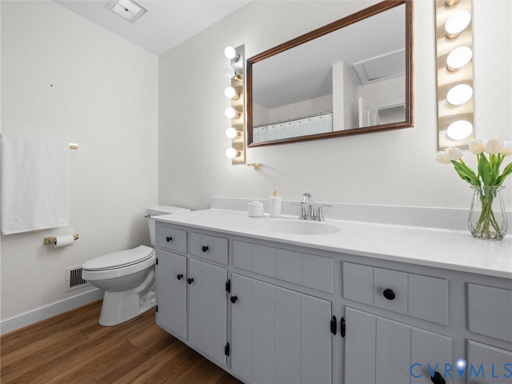 Wood-finish flooring with a white vanity featuring a single basin sink