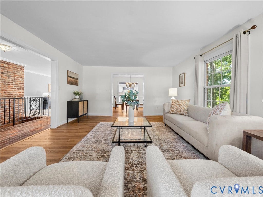 Expansive living area featuring wood-finish flooring, white walls, and a large window