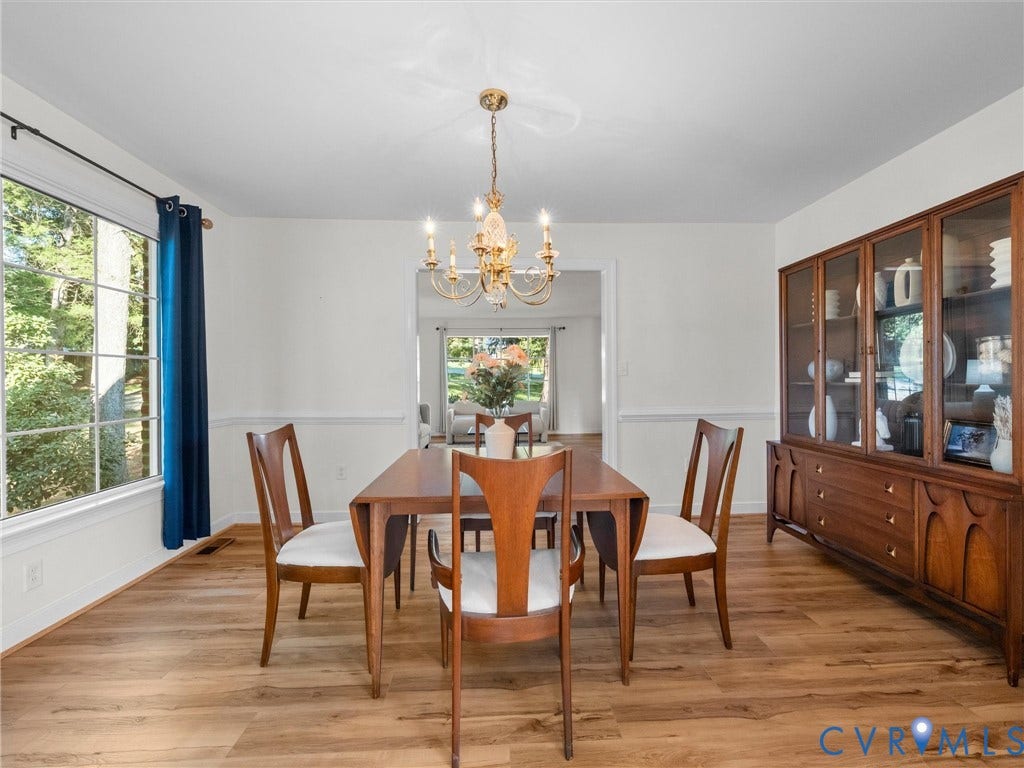 Recessed wall paneling, wood-finish flooring, and an elegant chandelier