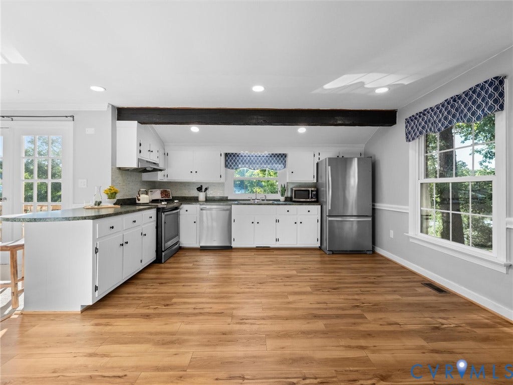Kitchen featuring white cabinetry, stainless steel appliances, wood-finish flooring, recessed lighting, and a kitchen island with seating