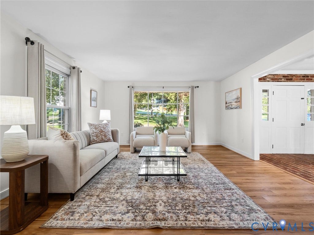 Hardwood flooring, ample natural light from multiple windows, white painted walls, and a multi-panel door with side lights