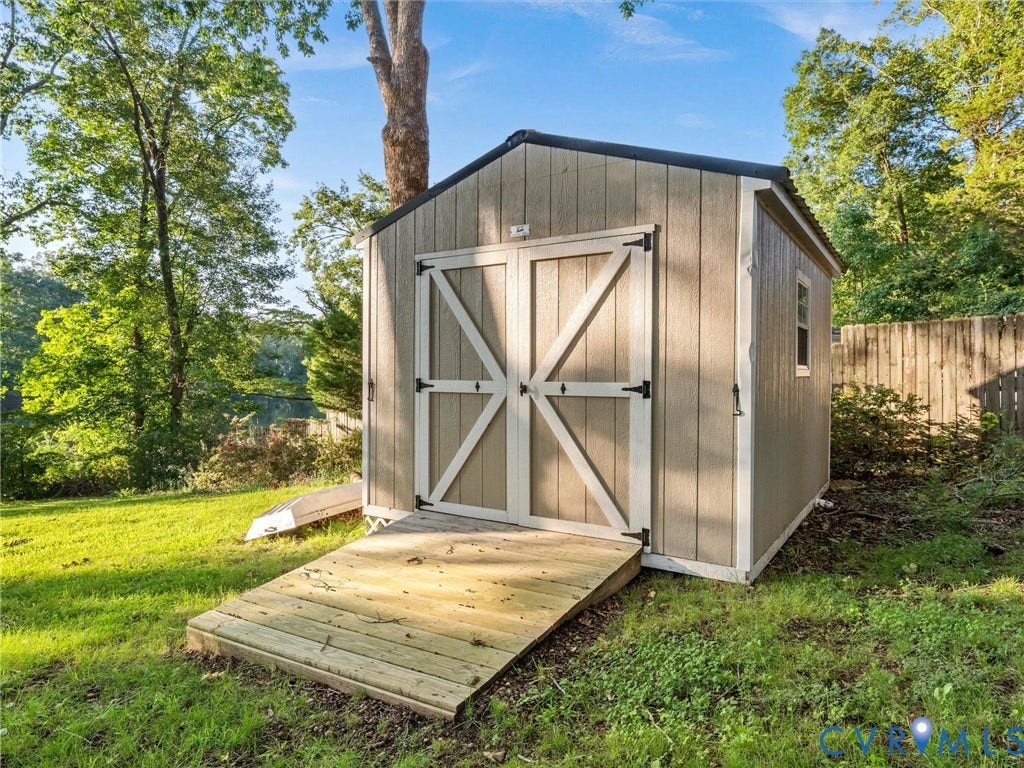 Detached utility shed with a gable roof, double barn doors, and a wood ramp