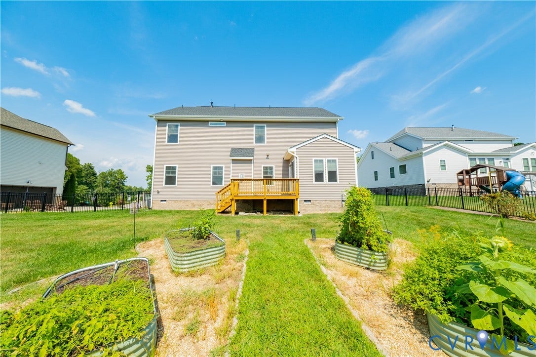 Two-story exterior with siding, featuring a wood deck and an expansive rear lawn
