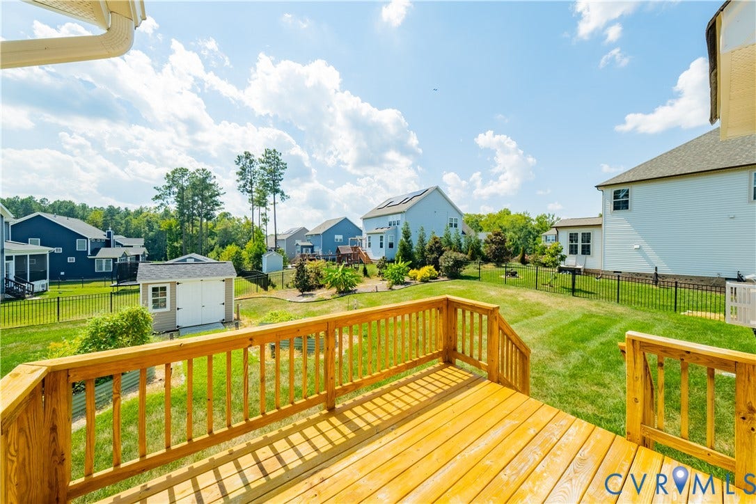 Spacious backyard featuring a wood deck, manicured lawn, and a storage shed