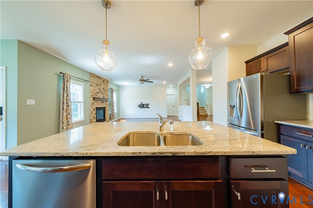Kitchen island with a double basin sink, granite countertop, and integrated dishwasher