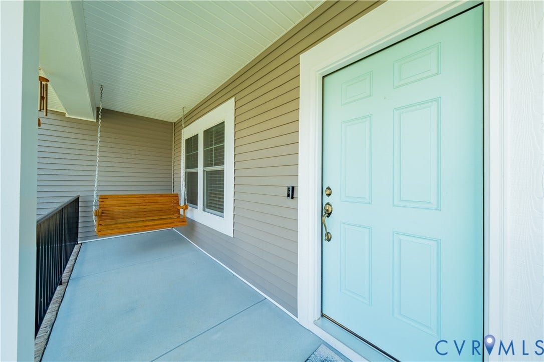 Front porch with siding exterior, light blue paneled entry door, black metal railing, and a window with white trim