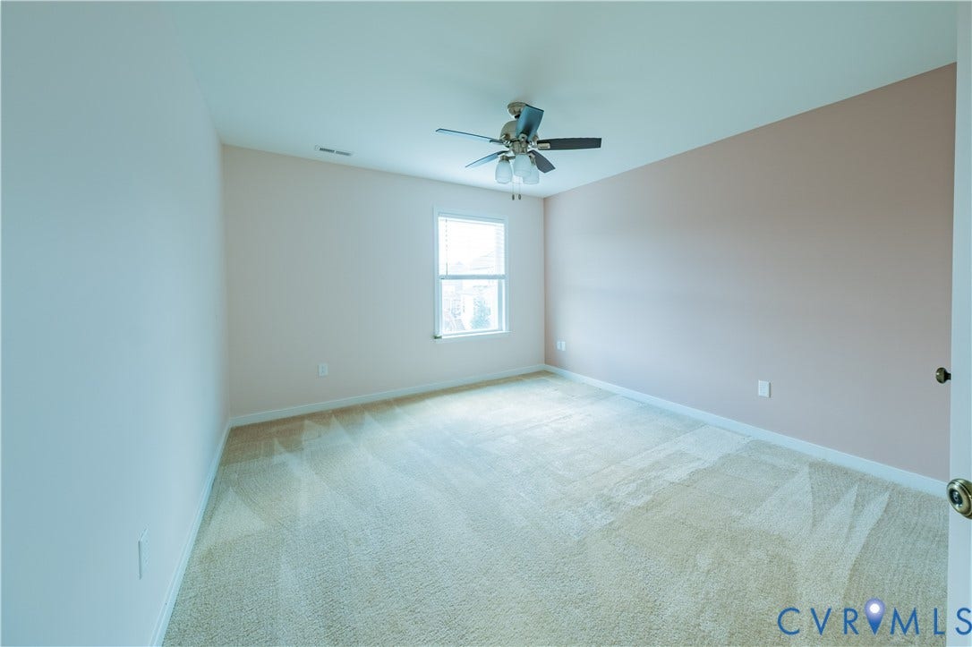 Carpeted room with a ceiling fan, single window, and light-colored walls