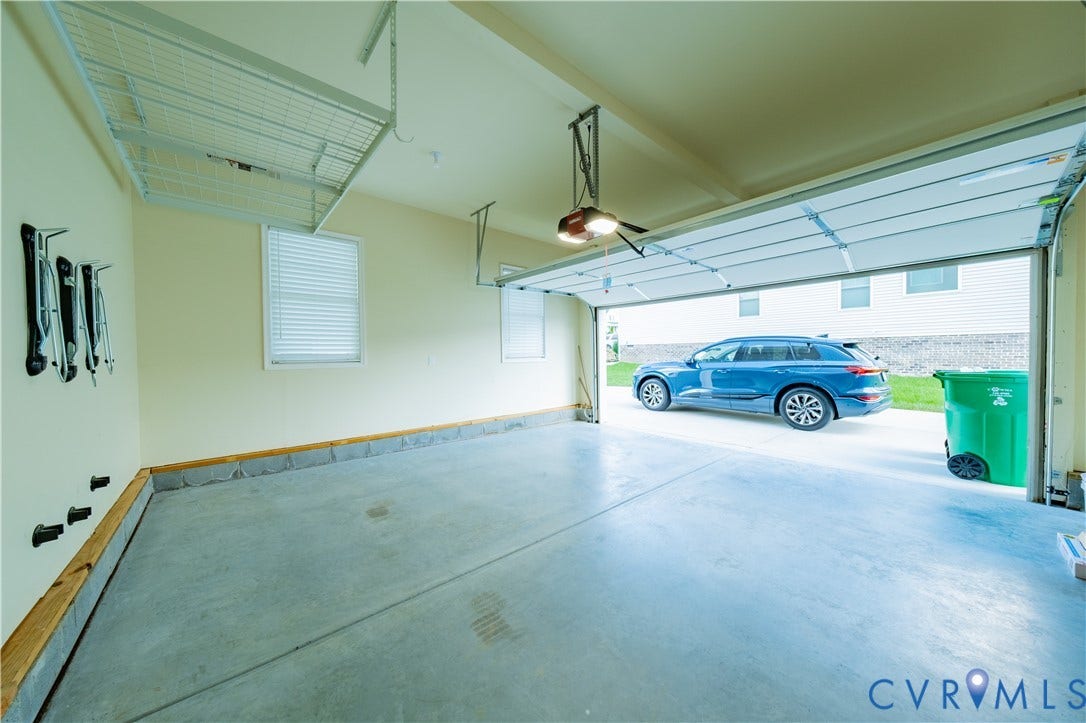 Attached overhead storage, concrete flooring, and a single window with blinds