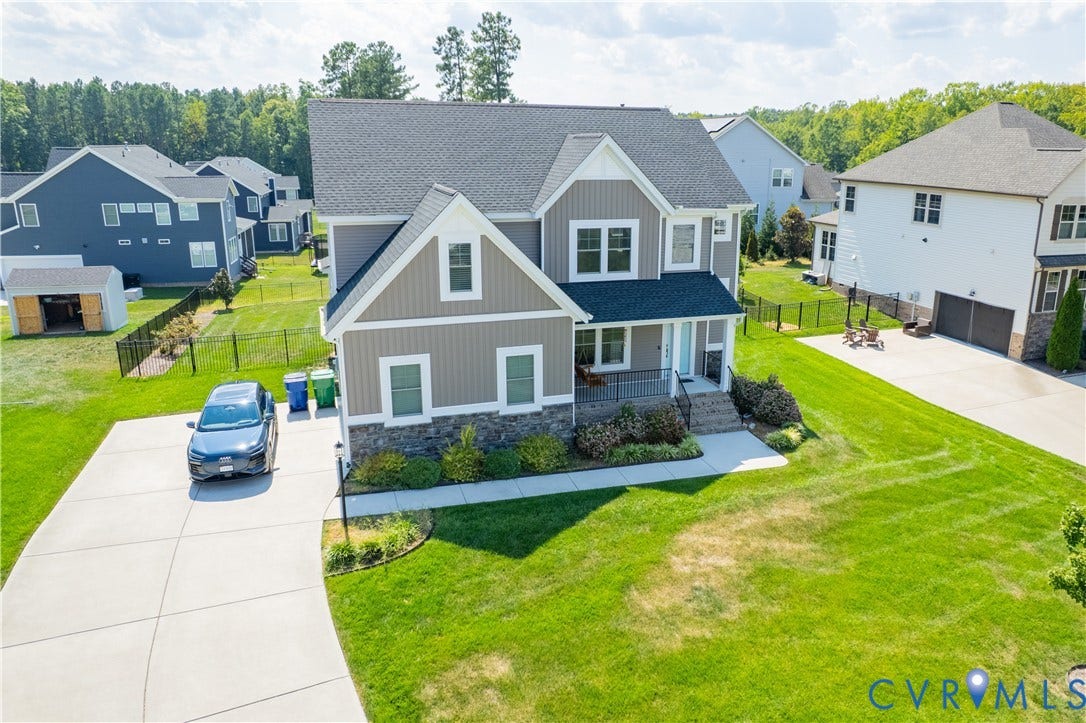 Two-story residence featuring a dark gray roof, light gray siding, and stone accents