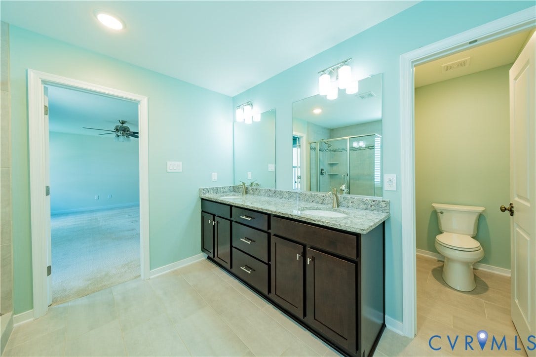 Double vanity with granite countertop, dual undermount sinks, and dark wood cabinetry