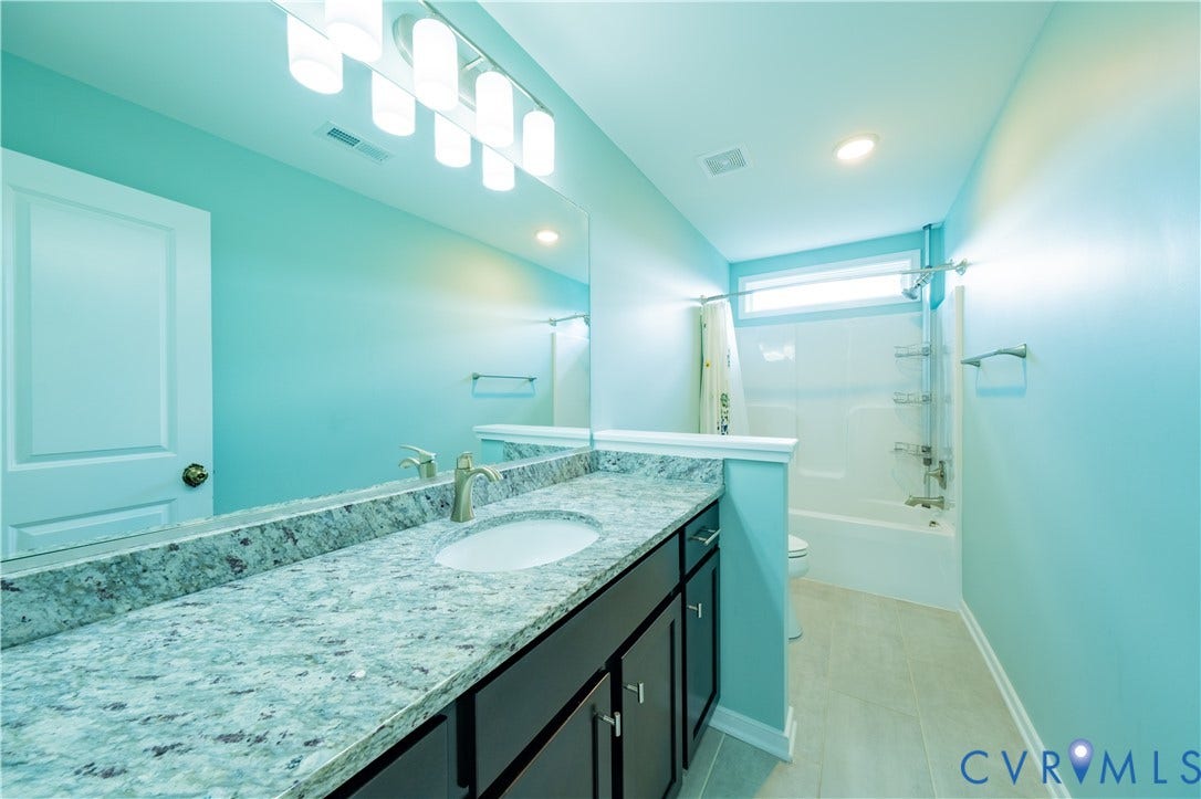 Elongated vanity with a double sink, light-toned countertop, and dark cabinetry