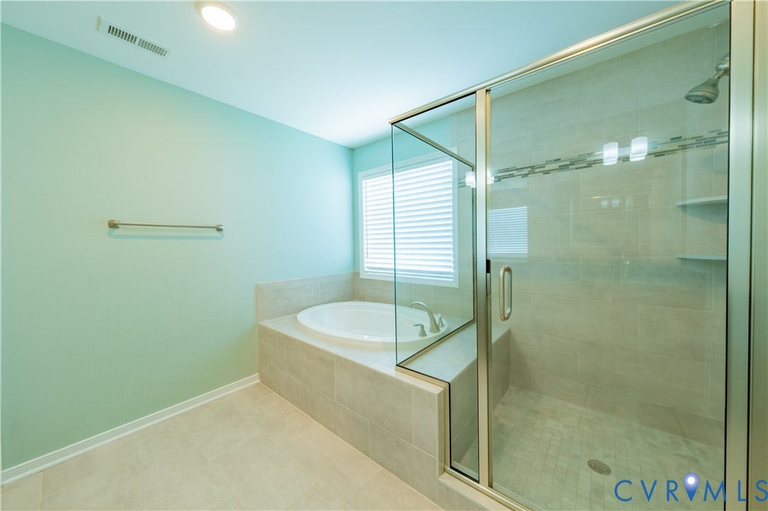 Built-in soaking tub with tiled surround, glass-enclosed shower with tiled walls, and recessed lighting