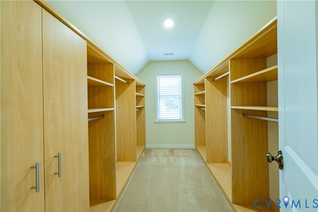 Walk-in closet featuring extensive built-in shelving, hanging rods, and cabinetry with brushed nickel hardware