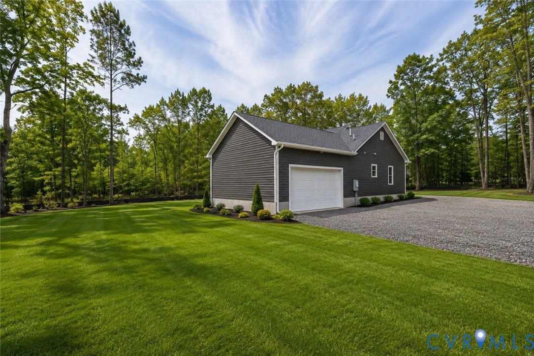 Lot 1A Tabscott Road, Columbia, VA 23038 Expansive lawn surrounding a charcoal-colored siding structure with a white garage door, gravel driveway, and mature perimeter trees