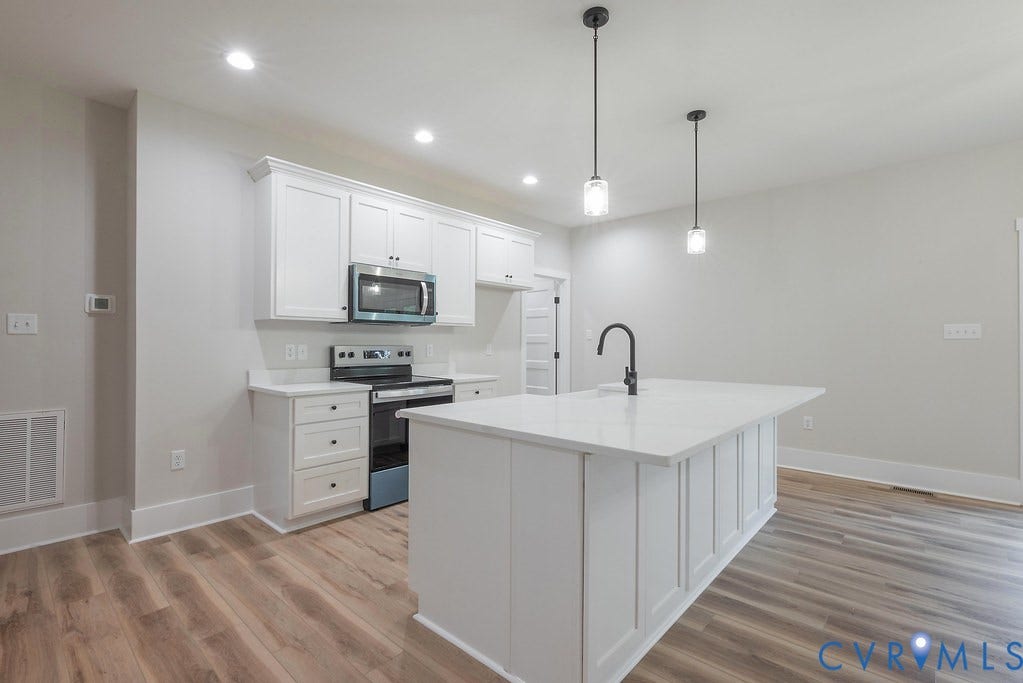 Lot 1A Tabscott Road, Columbia, VA 23038 Kitchen featuring white cabinetry, a central island with a sink, stainless steel appliances, wood-finish flooring, and recessed ceiling lights