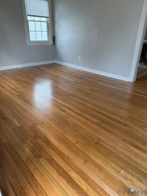 Hardwood flooring, light gray wall paint, white trim, and a window with blinds