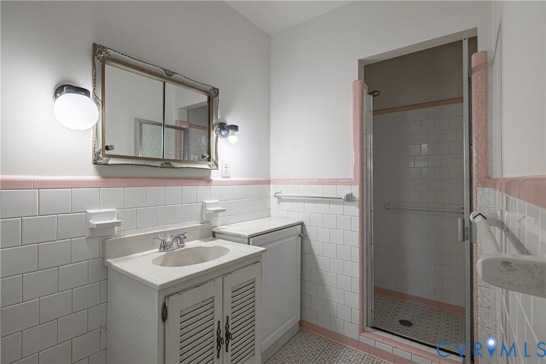 4532 Arrowhead Road, Statford Hills / Oxford, Richmond, VA 23235 White subway tile walls with pink trim accents, vanity with integrated sink, framed mirror, and a glass-enclosed shower