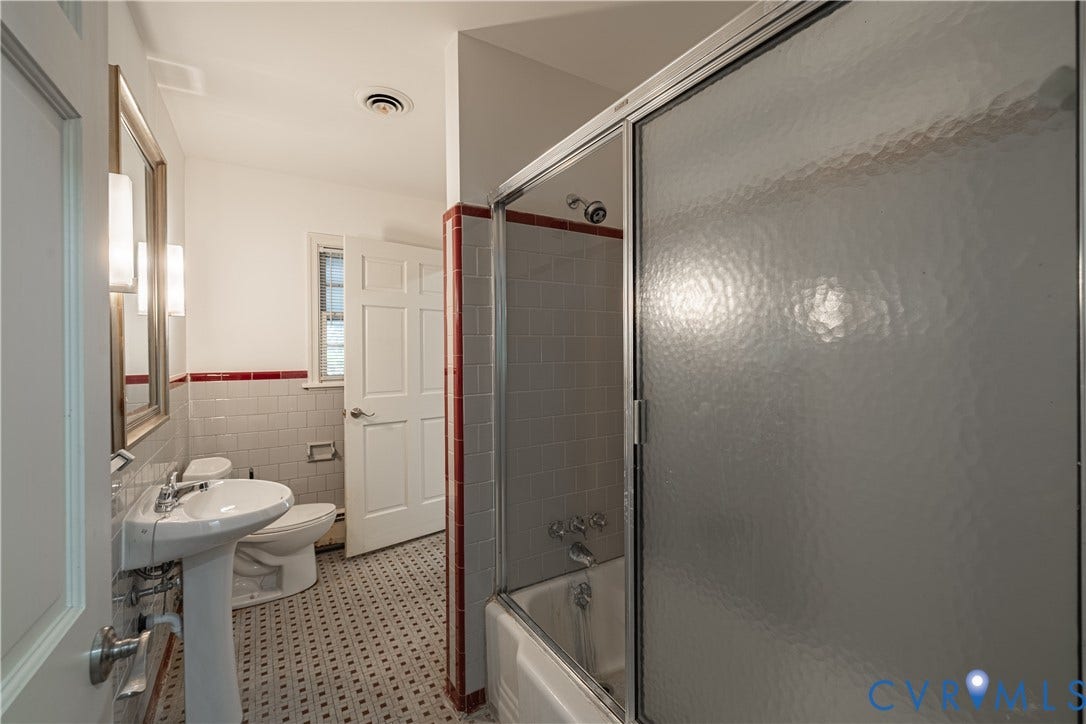4532 Arrowhead Road, Statford Hills / Oxford, Richmond, VA 23235 Pedestal sink, wall-mounted mirror, white subway tile with red accent trim, patterned floor tile, and bathtub with sliding glass doors