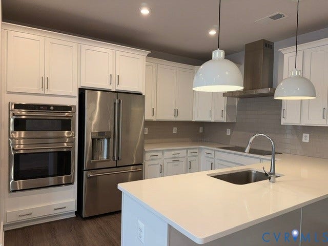 4113 Greybull Drive, #A, Gateway Square, Henrico, VA 23233 White cabinetry with crown molding, stainless steel appliances, light-toned countertops, gray subway tile backsplash, and wood-finish flooring