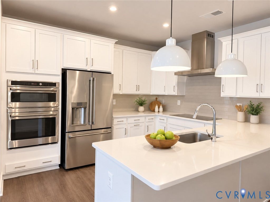 4113 Greybull Drive, #A, Gateway Square, Henrico, VA 23233 Virtually staged. White shaker cabinetry with crown molding, stainless steel appliances, light-toned countertop surfaces, a subway tile backsplash, and two pendant lights over the kitchen island