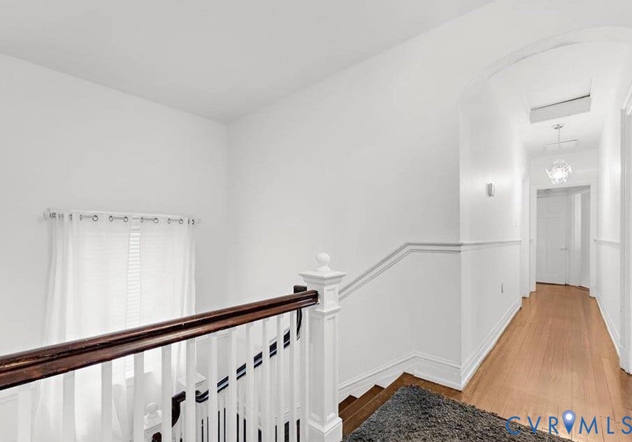 710 N Arthur Ashe Boulevard, Historic Fan District, Richmond, VA 23220 Hardwood flooring, white painted walls, white railing with wood-finish handrail, decorative wall molding, and an arched hallway