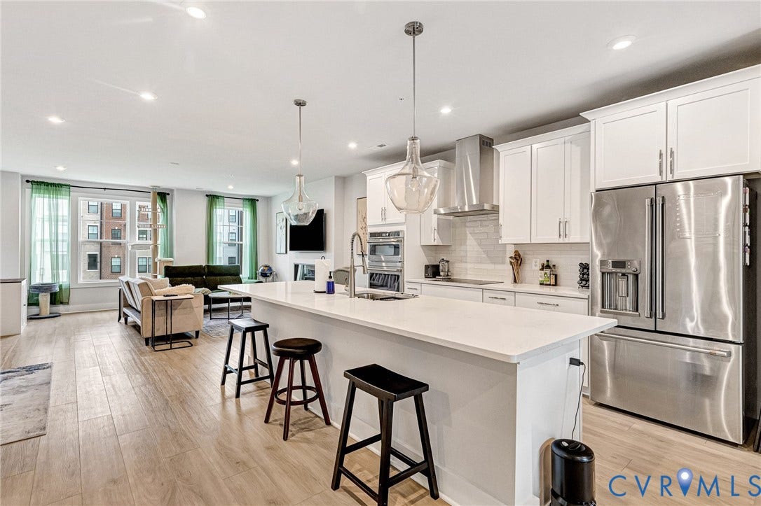 528 Greybull Walk, #B, Glen Allen, VA 23233 Gourmet kitchen with white cabinetry and stainless steel appliances, central island with seating, pendant lighting, and wood-finish flooring throughout
