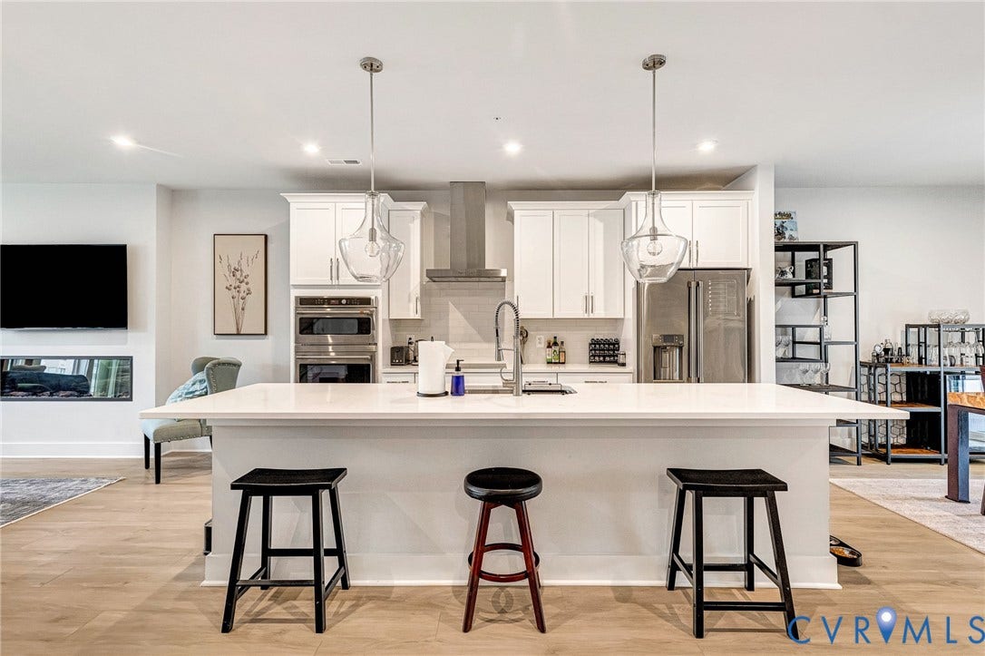 528 Greybull Walk, #B, Glen Allen, VA 23233 Open-concept kitchen featuring an expansive island, stainless steel appliances, white cabinetry, and wood-finish flooring