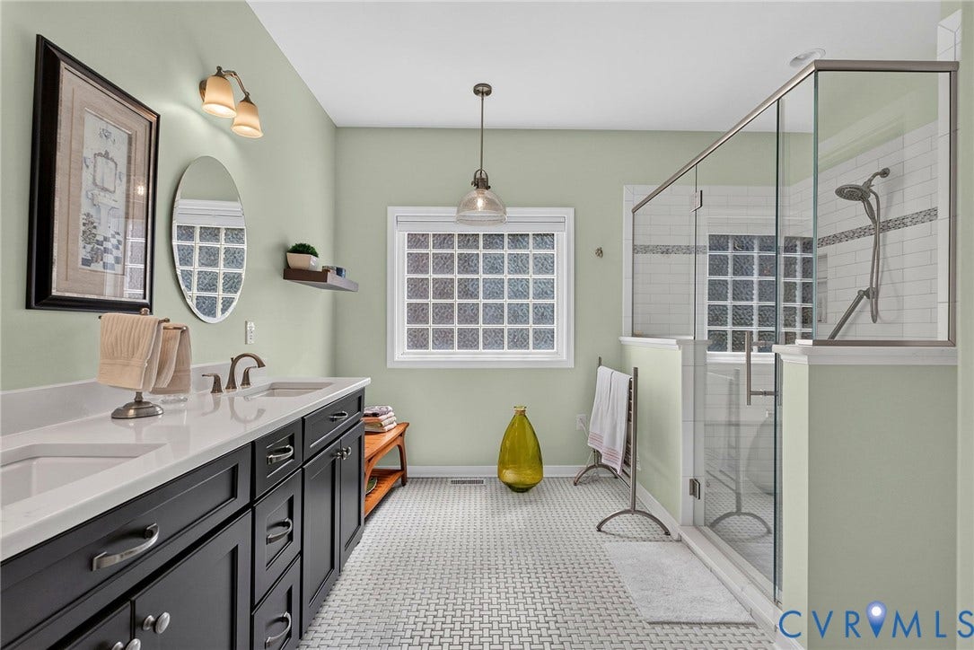 Retreat to the spacious ensuite with a double vanity, crisp white tile, and a large glass-enclosed walk-in shower.