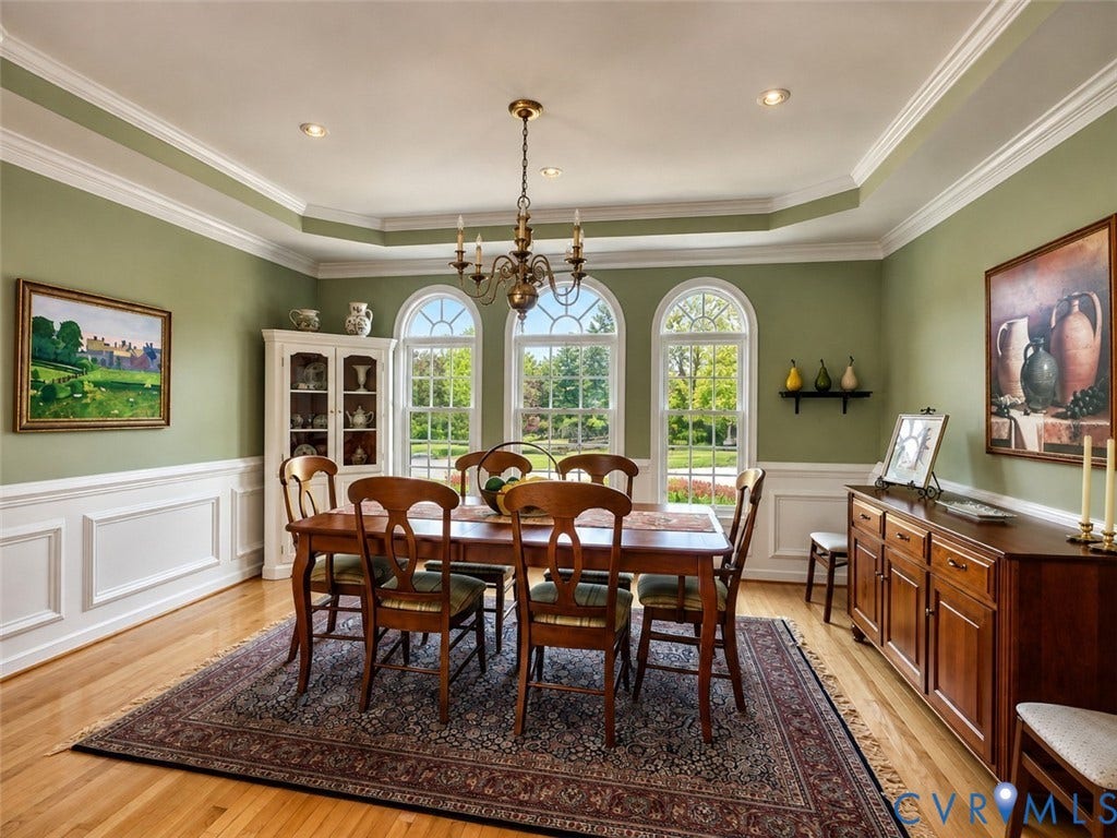 Elegant formal dining room featuring classic millwork, arched windows, and hardwood floors.