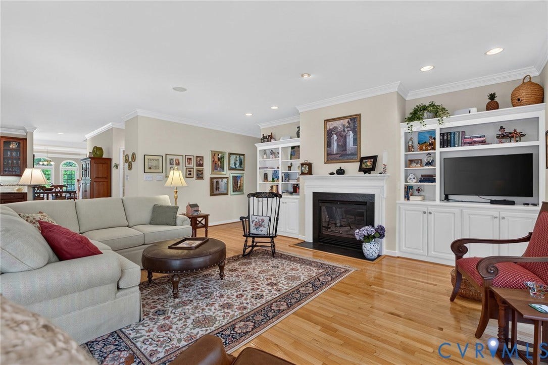 Spacious, light-filled living room featuring hardwood floors, a gas fireplace, and built-ins.