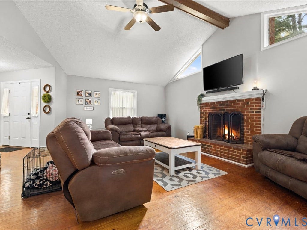 12724 S Chester Road, Chesterfield, VA 23831 Brick wood burning fireplace with metal screen, wood-finish flooring, ceiling fan, and triangular transom windows