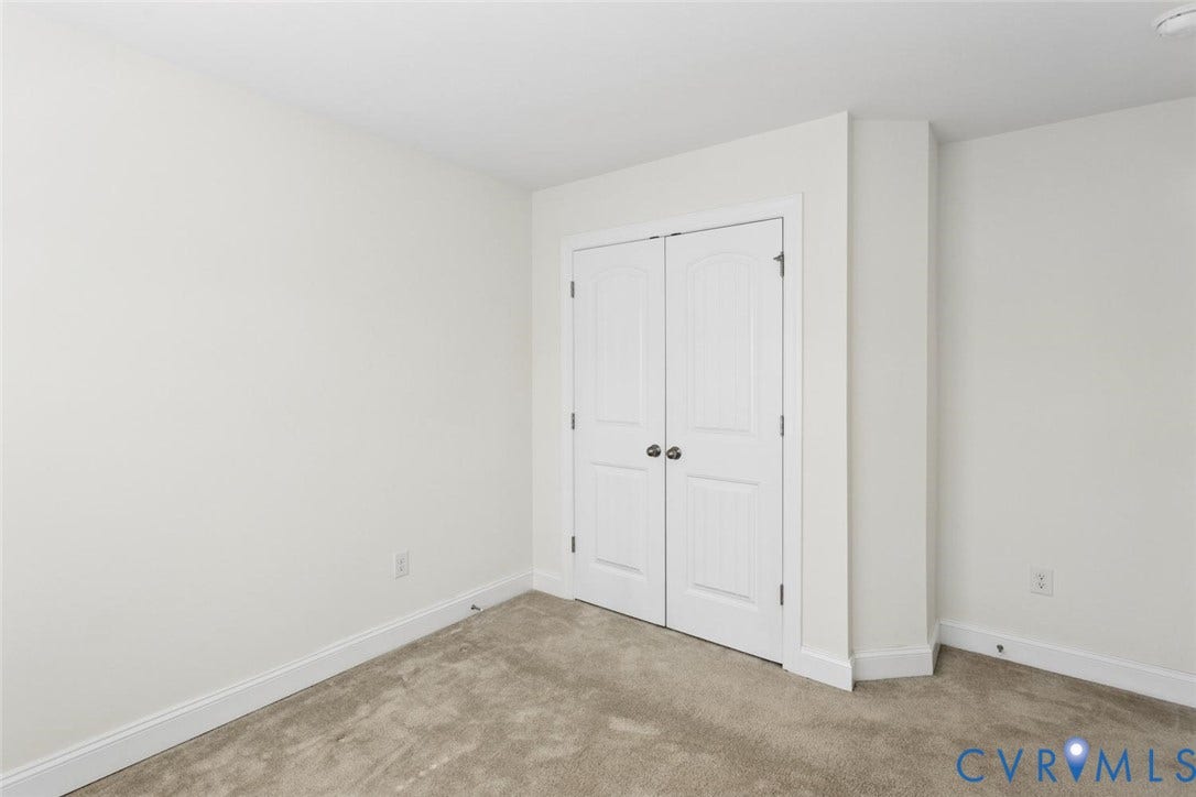 Neutral wall paint, carpet flooring, and white bi-fold closet doors.