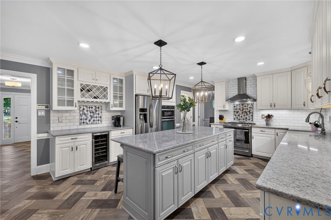 12800 Leffingwell Court, Henrico, VA 23233 Kitchen featuring wood-finish flooring, white cabinetry, integrated stainless steel appliances, a large island with a light-colored countertop, and two ceiling-mounted light fixtures