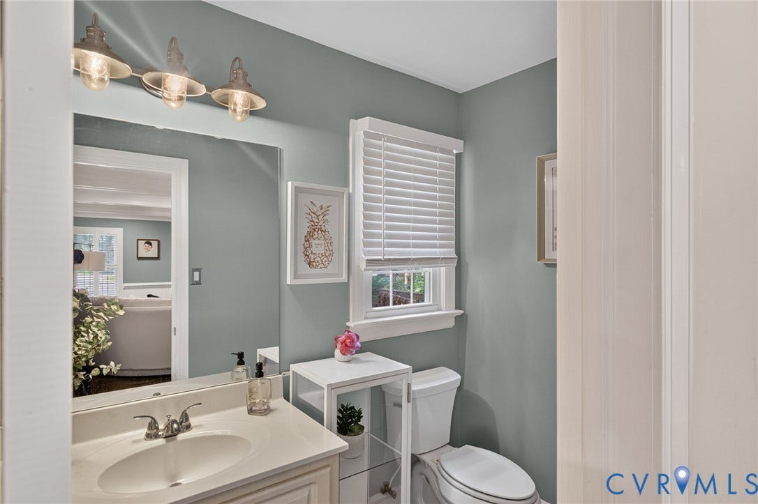 12800 Leffingwell Court, Henrico, VA 23233 Bathroom featuring a vanity with an undermount sink, a wall-mounted mirror, a window with white blinds, and a white toilet
