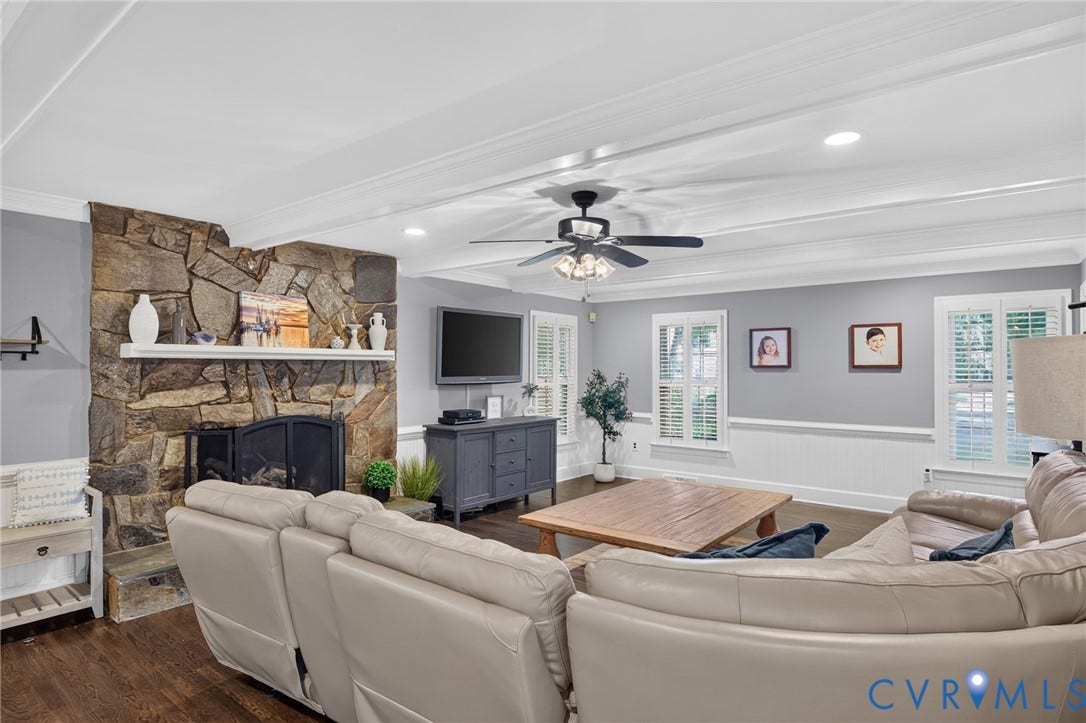 12800 Leffingwell Court, Henrico, VA 23233 Stone fireplace with a white mantel, wood-finish flooring, white coffered ceiling, ceiling fan with integrated lighting, and white plantation shutters